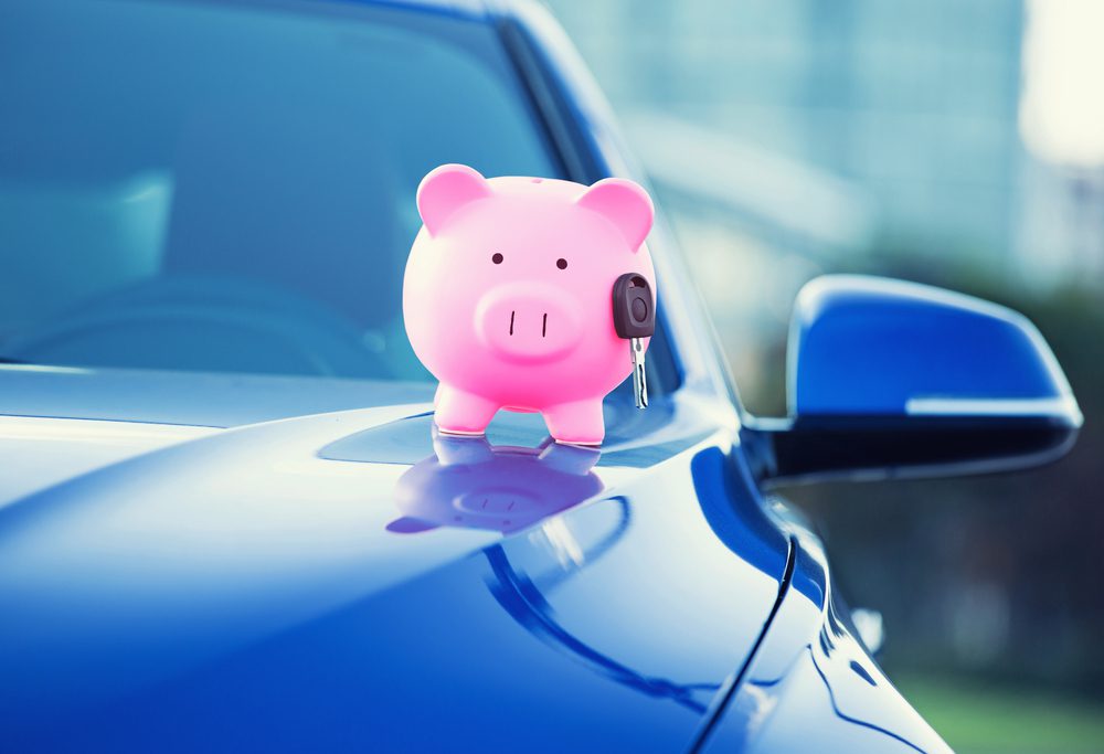 a piggy bank with a key on the hood of a car